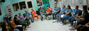 Women's Community Correctional Center residents and community guests sit in a circle listening to the person holding the yarn community ball, indicating that she has the floor.