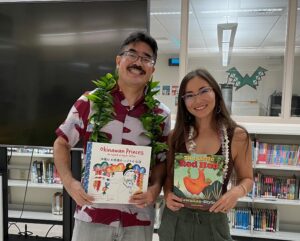 Lee Tonouchi and Jen Morgan wearing lei smile holding children's books.