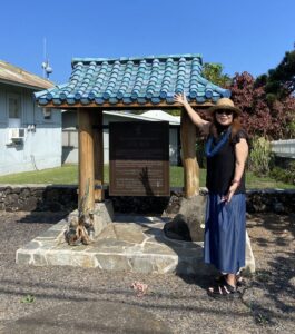 Dr. Patsy Iwasaki stands next to the memorial to Goto in Hāmākua on Hawaiʻi Island.